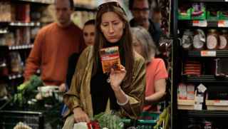 A woman carefully reading the label on a product at the Coop.