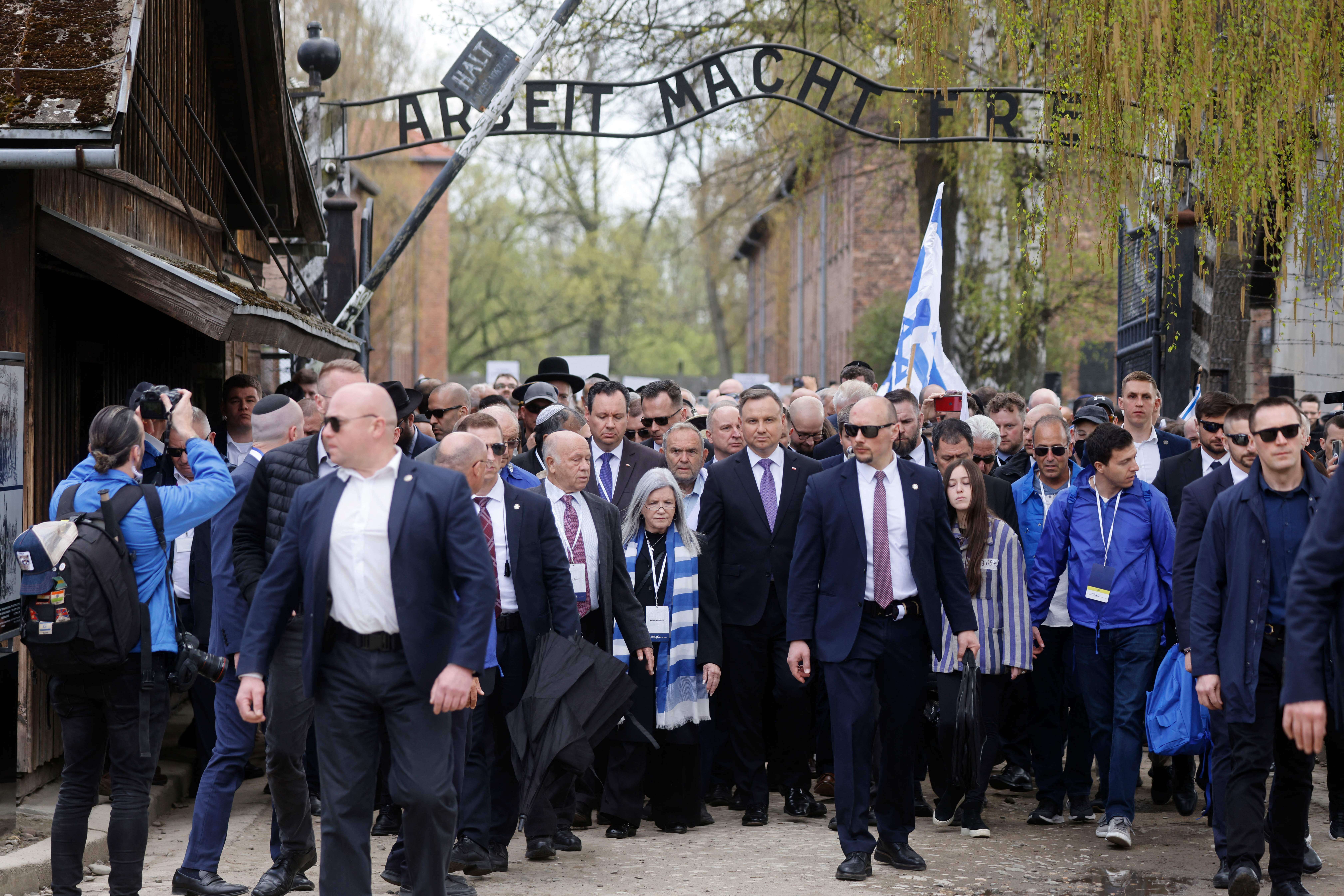 Polish President Andrzej Duda (C-R) walks with other participants through the main gate of the former Auschwitz-Birkenau camp with the lettering 'Work makes you free' (Arbeit macht frei) during The March of the Living in Oswiecim, Poland on April 28, 2022