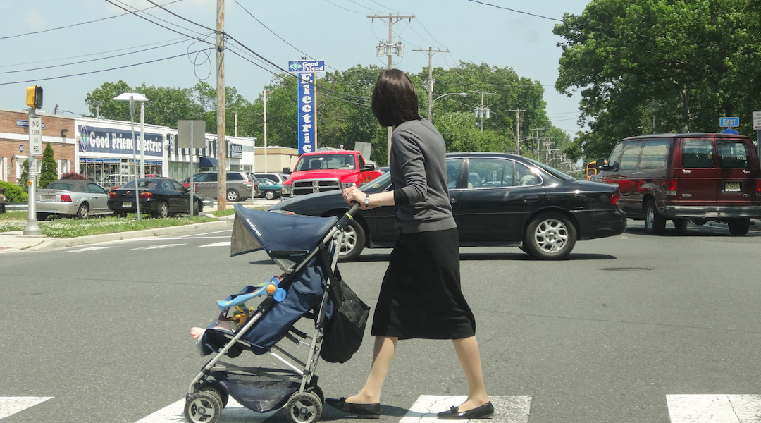 An Orthodox woman pushes a stroller in Lakewood, N.J., in 2013. The population in the largely Haredi Orthodox town has boomed in the past couple of decades. (Credit: Dennis Fraevich/Flickr)