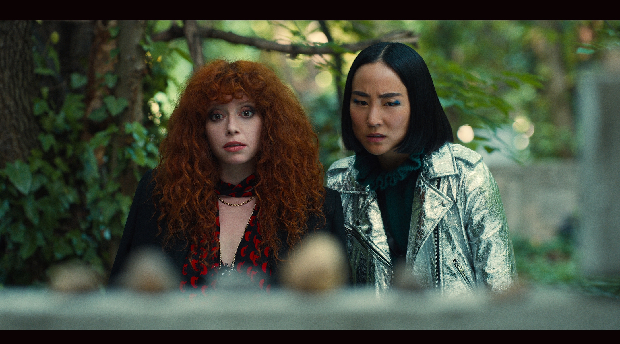 Nadia Vulvokov (Natasha Lyonne) and her friend Maxine (Greta Lee) encounter the grave of a Hungarian priest who saved Jews during the Holocaust, in Season 2 of “Russian Doll.” (Netflix)