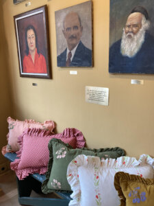 The photo shows a bench with ruffled pillows and three portraits of "townspeople" in the fictional village of Barrow's Green.
