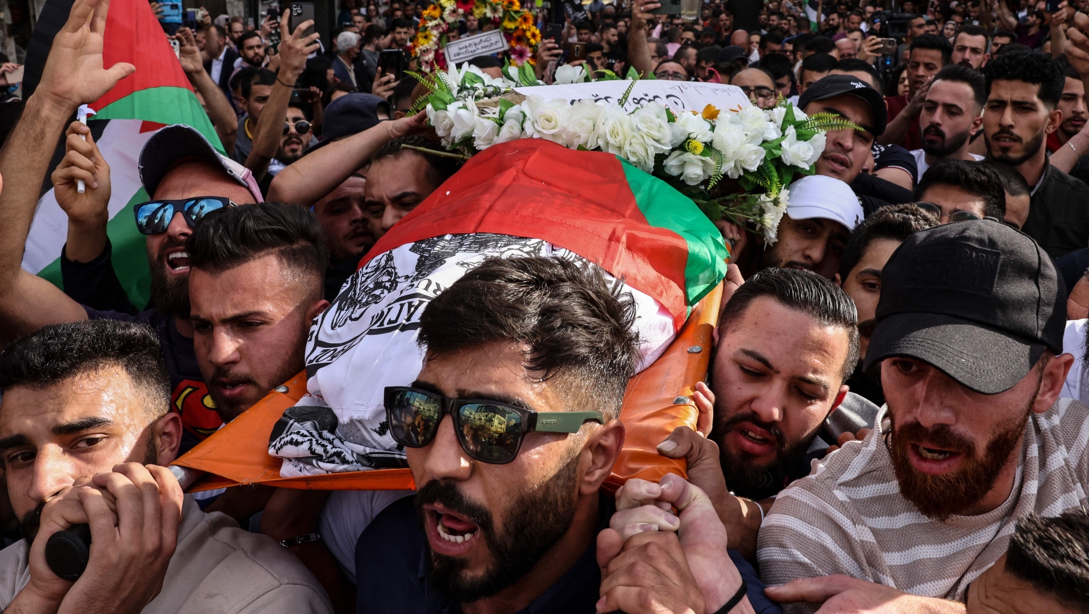 Palestinians carry the flag-draped body of veteran Al-Jazeera journalist Shireen Abu Akleh as it is carried toward the offices of the news channel in the West Bank city of Ramallah, May 11, 2022. (Ronaldo Schemidt/AFP via Getty Images)