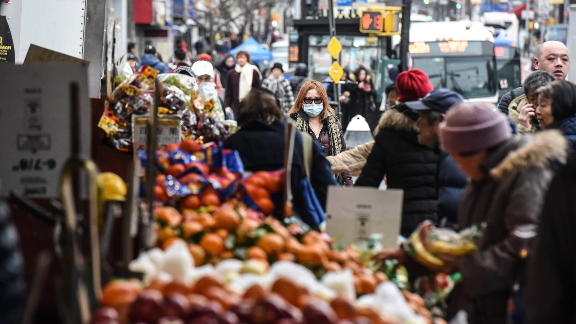 A pedestrian wearing a face mask walks along a street in the Flushing neighborhood of Queens.