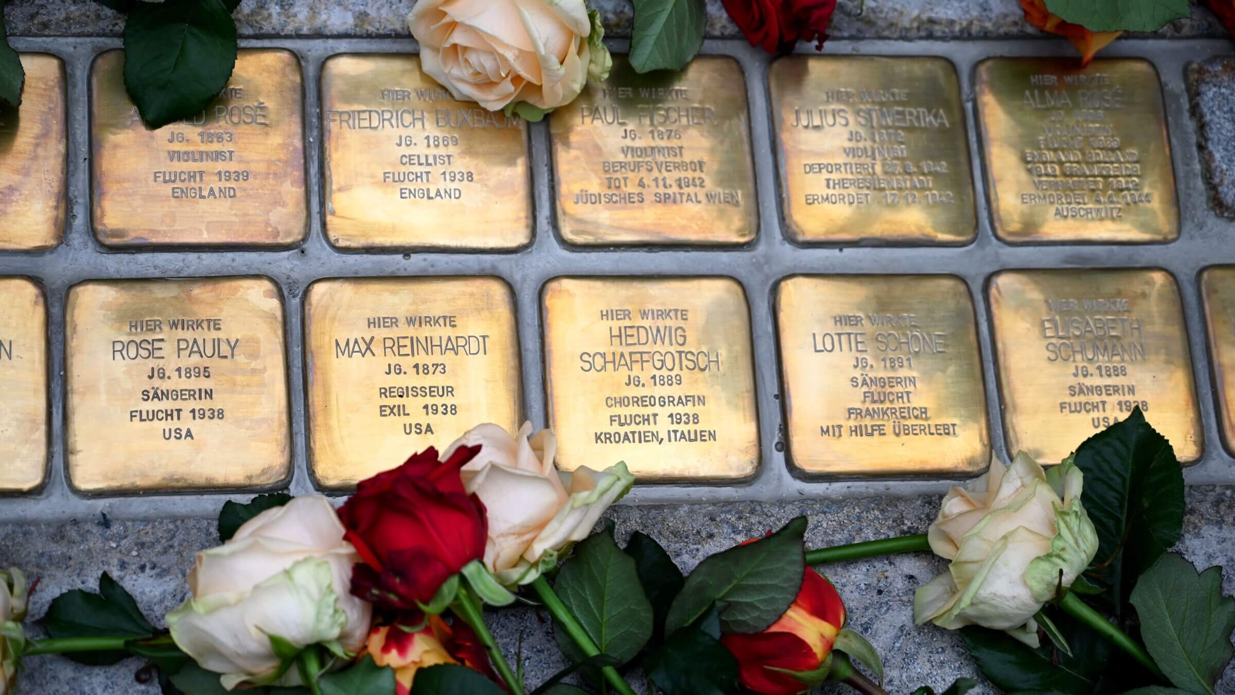 brass plaques, surrounded by roses, commemorating victims of Holocaust