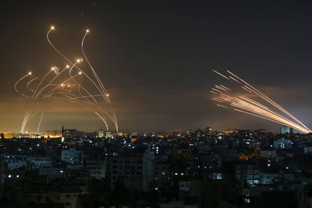 The Israeli Iron Dome missile defense system (L) intercepts rockets (R) fired by the Hamas movement towards southern Israel from Beit Lahia in the northern Gaza Strip as seen in the sky above the Gaza Strip overnight on May 14, 2021.