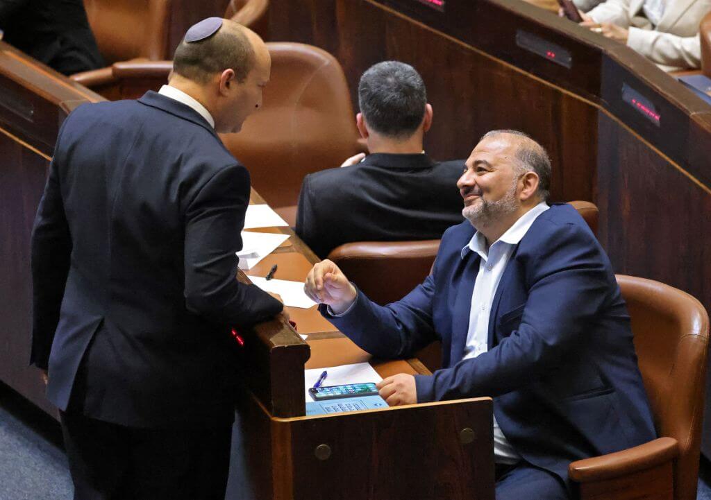 Head of Israel's right-wing Yamina party Naftali Bennett (L) chats with Mansour Abbas, head of the conservative Islamic Raam party during a special session to vote on a new government at the Knesset in Jerusalem, on June 13, 2021.