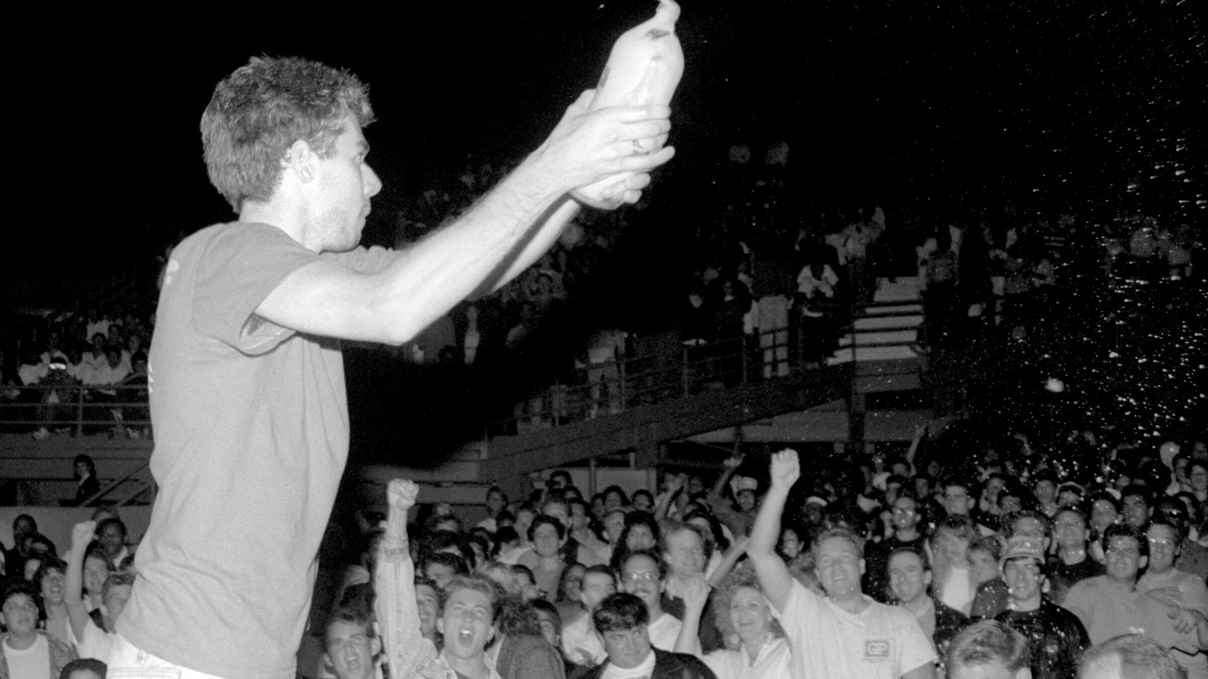 LOS ANGELES, CA - JUNE, 1987: American rapper, bass player and filmmaker Adam Yauch, aka MCA, (1964-2012) of the American hip hop group The Beastie Boys, throws beer on the crowd during a concert circa June, 1987 at the Greek Theatre in Los Angeles, California. (Photo by Lester Cohen/Getty Images)