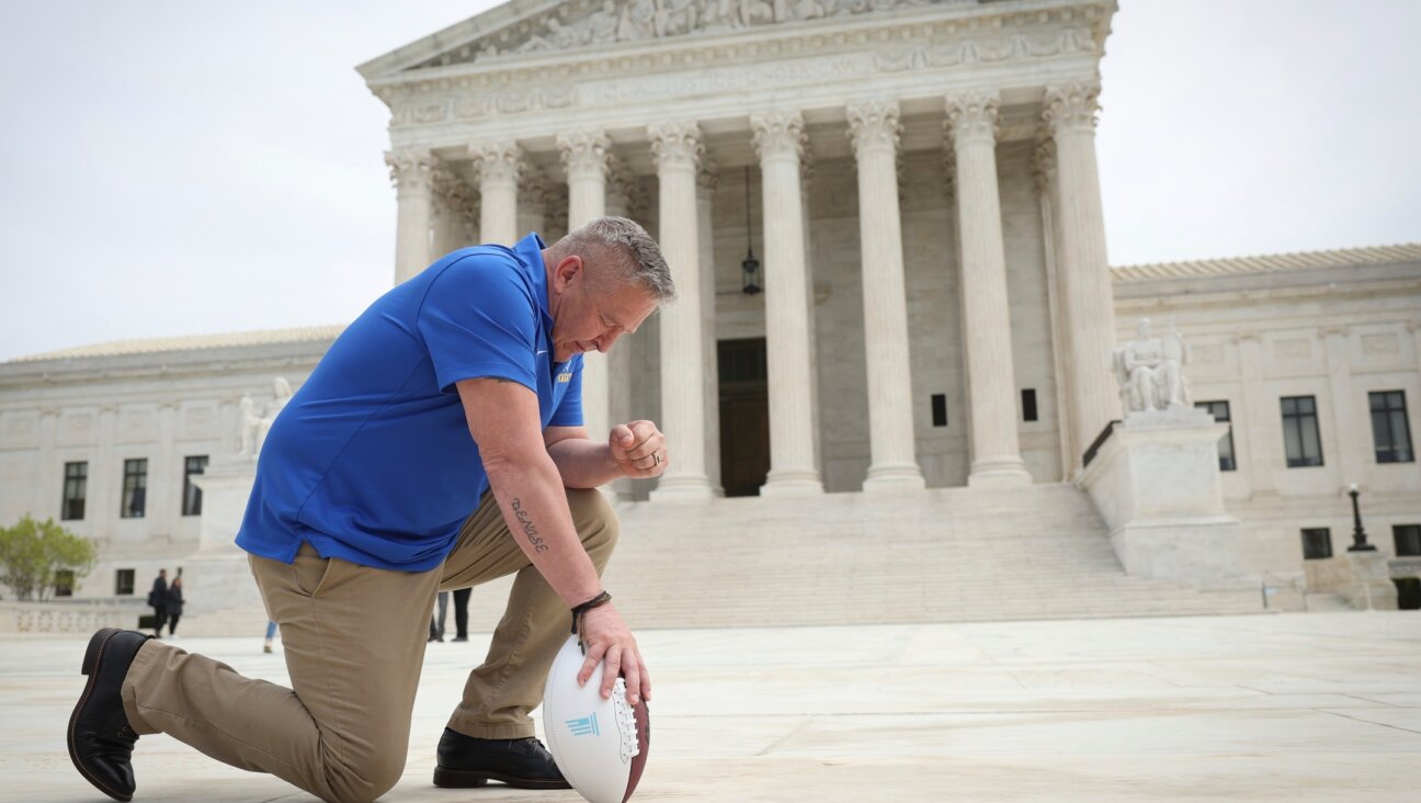 Assistant football coach Joe Kennedy takes a knee in front of the U.S. Supreme Court after his legal case about prayer in public school was argued before the court in April 2022.  (Win McNamee/Getty Images)