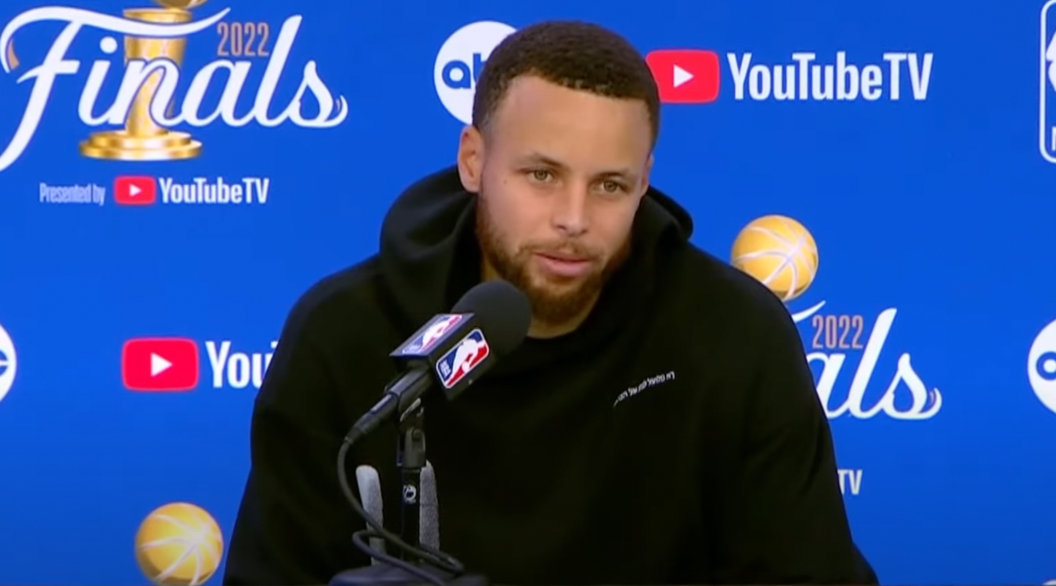 Stephen Curry sporting a sweatshirt with Hebrew on it during an NBA Finals postgame press conference, June 10, 2022. (Screenshot from YouTube)