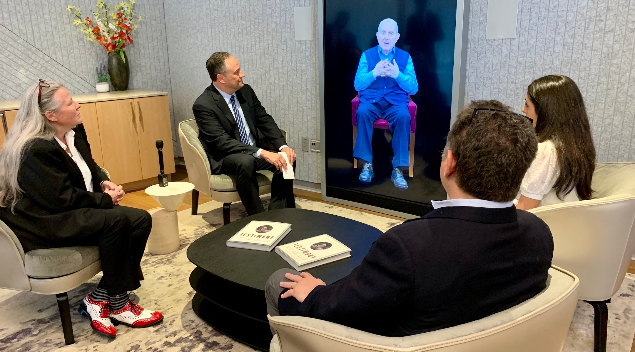 Second Gentleman Doug Emhoff, second from left, speaks to an interactive artificial intelligence video of Holocaust survivor Pinchas Gutter. (Jacob Gurvis)