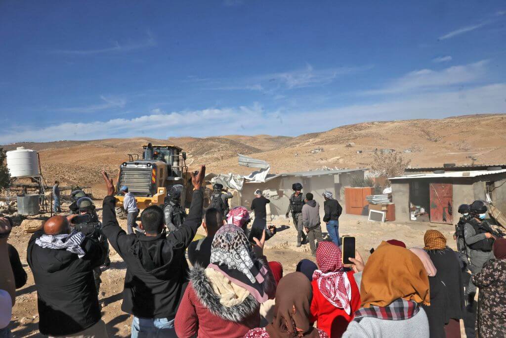 Palestinians gather as Israeli bulldozers demolish makeshift houses in the village of al-Fikhit, in the occupied West Bank on January 12, 2022.