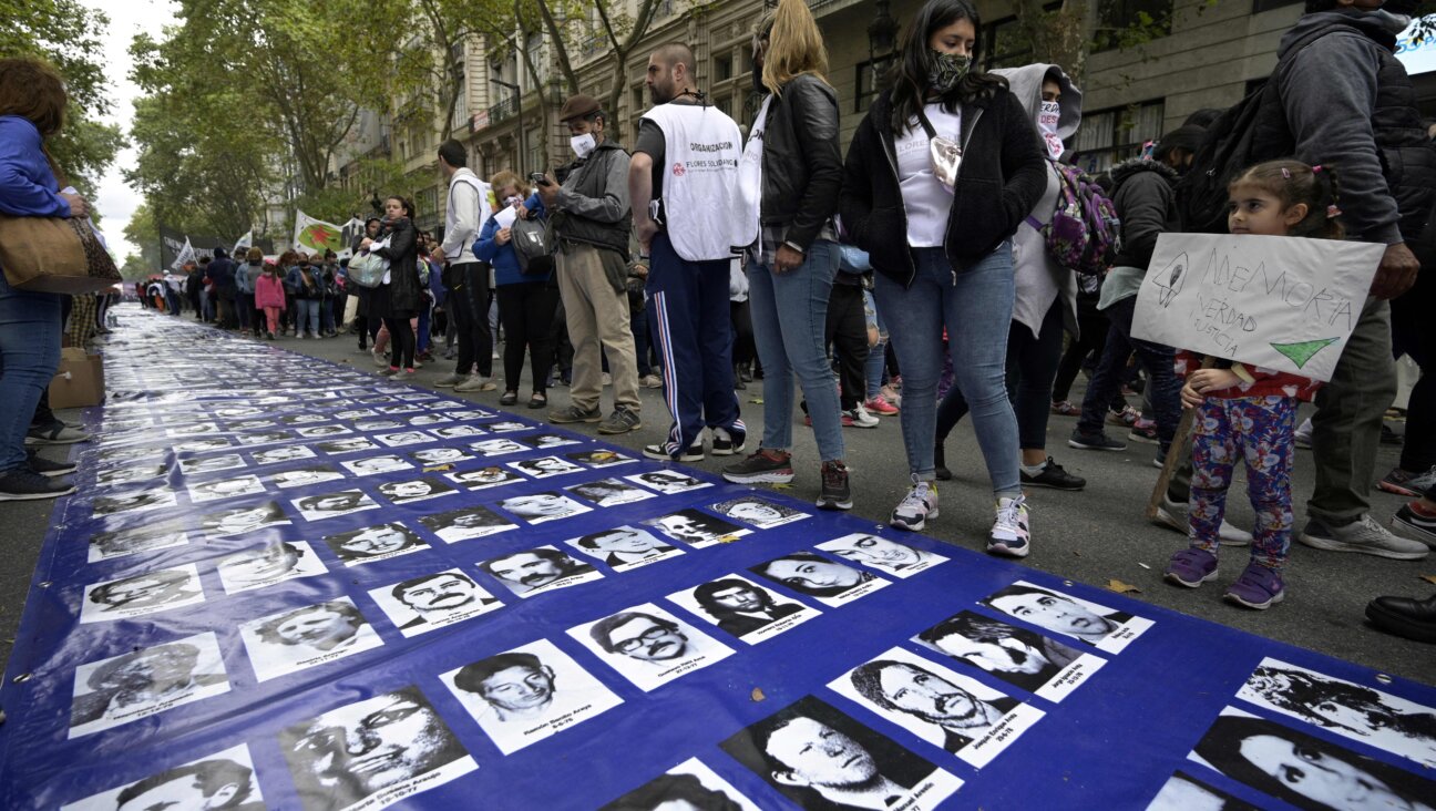 A girl holds a banner reading “Memory, Truth, Justice” next to a large banner with portraits of people disappeared during the military dictatorship (1976-1983), at a gathering to commemorate the 46th anniversary of the coup, at Plaza de Mayo Square in Buenos Aires.