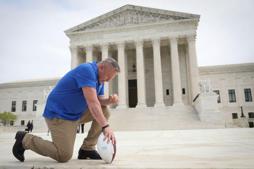 Former Bremerton High School assistant football coach Joe Kennedy takes a knee in front of the U.S. Supreme Court.