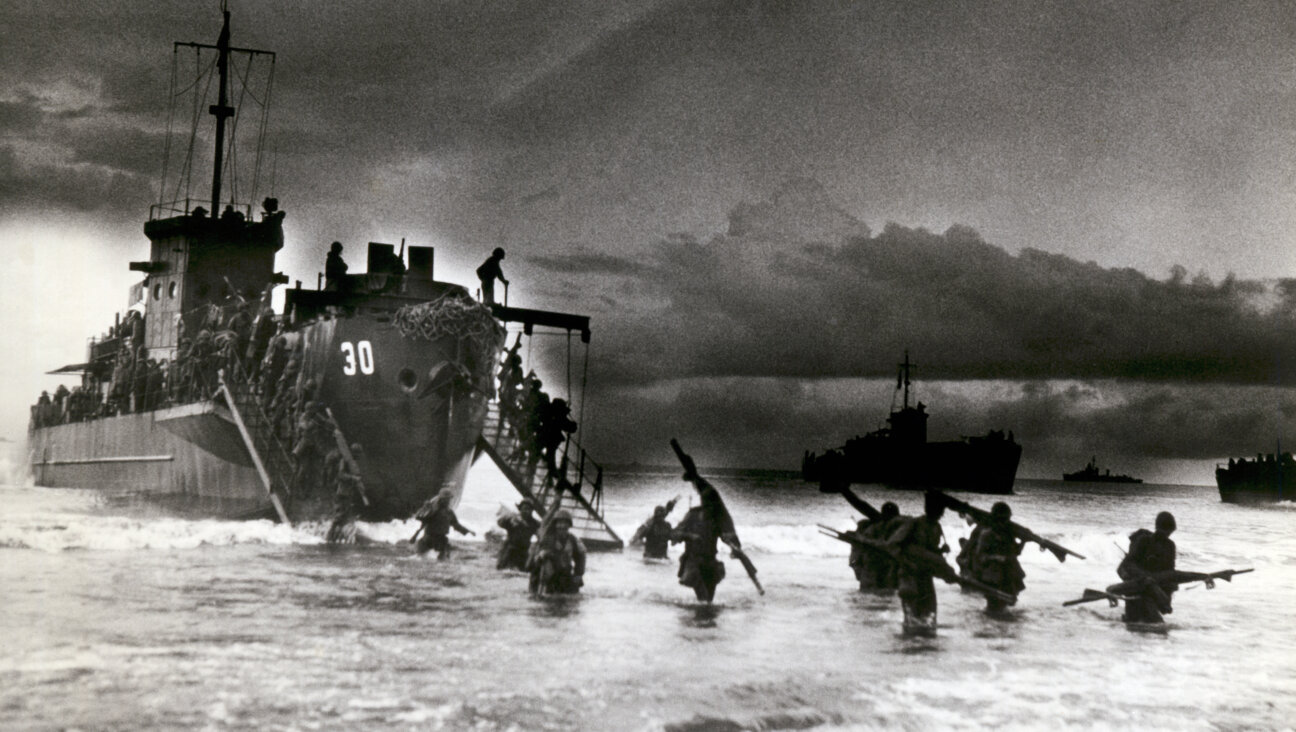 View of Allied troops from a transport vessel, among them medics with stretchers over their shoulders, as they wade ashore during the invasion of Normandy, France, in June 1944.