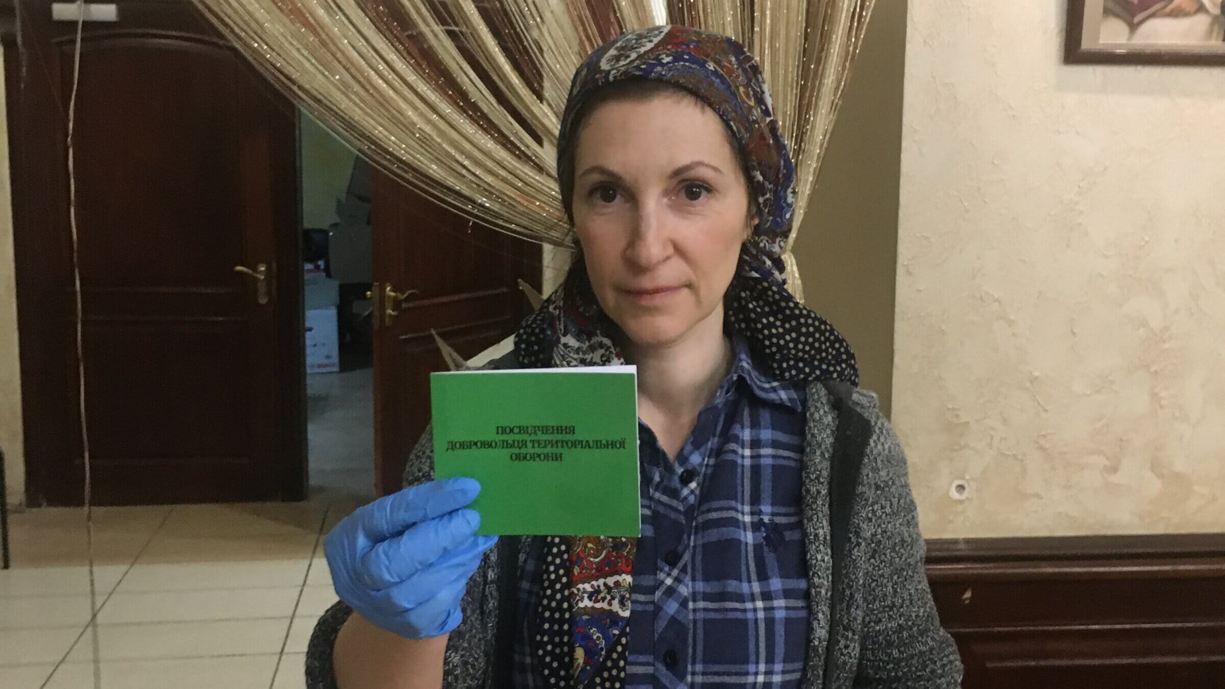 Rachel Strugatsky, at Kyiv's Brodsky Synagogue, holds up her identification card for Ukraine's Territorial Defense Forces, for which she volunteered days after Russia invaded Ukraine on Feb. 24, 2022.