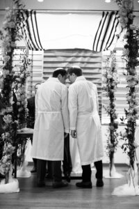 Two men in white robes and yarmulkes seen from behind