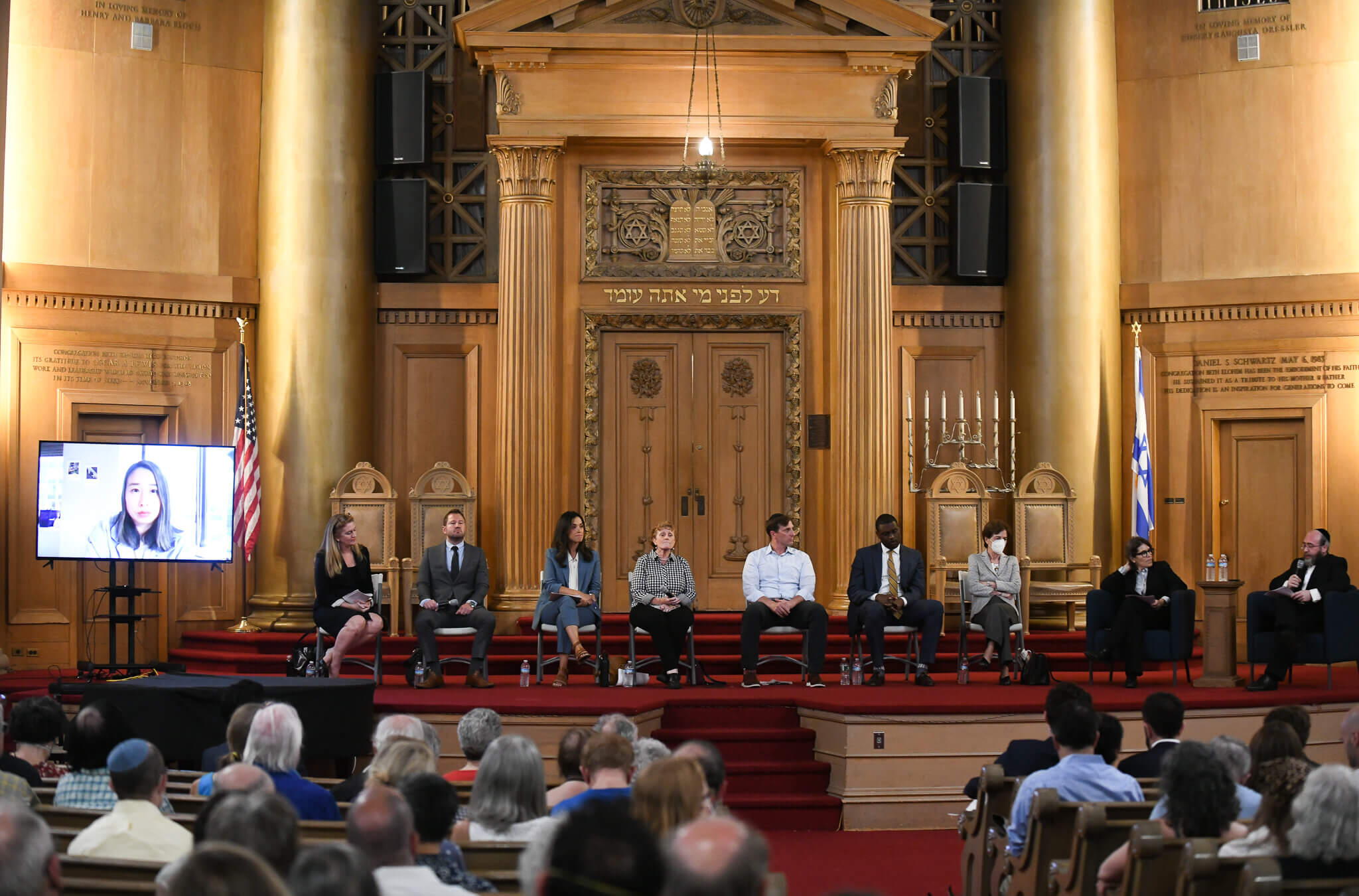 Assemblymember Yuh-Line Niou (left, on video screen), then from left to right, former public defender Maud Maron,  small business owner Brian Robinson, City Councilmember Carlina Rivera,  Assemblymember Jo Anne Simon,  former House impeachment counsel Dan Goldman, Rep. Mondaire Jones and former Rep. Elizabeth Holtzman at the candidate forum for New York's 10th Congressional District co-hosted by the Forward at Congregation Beth Elohim (CBE) in Brooklyn on July 26, 2022.