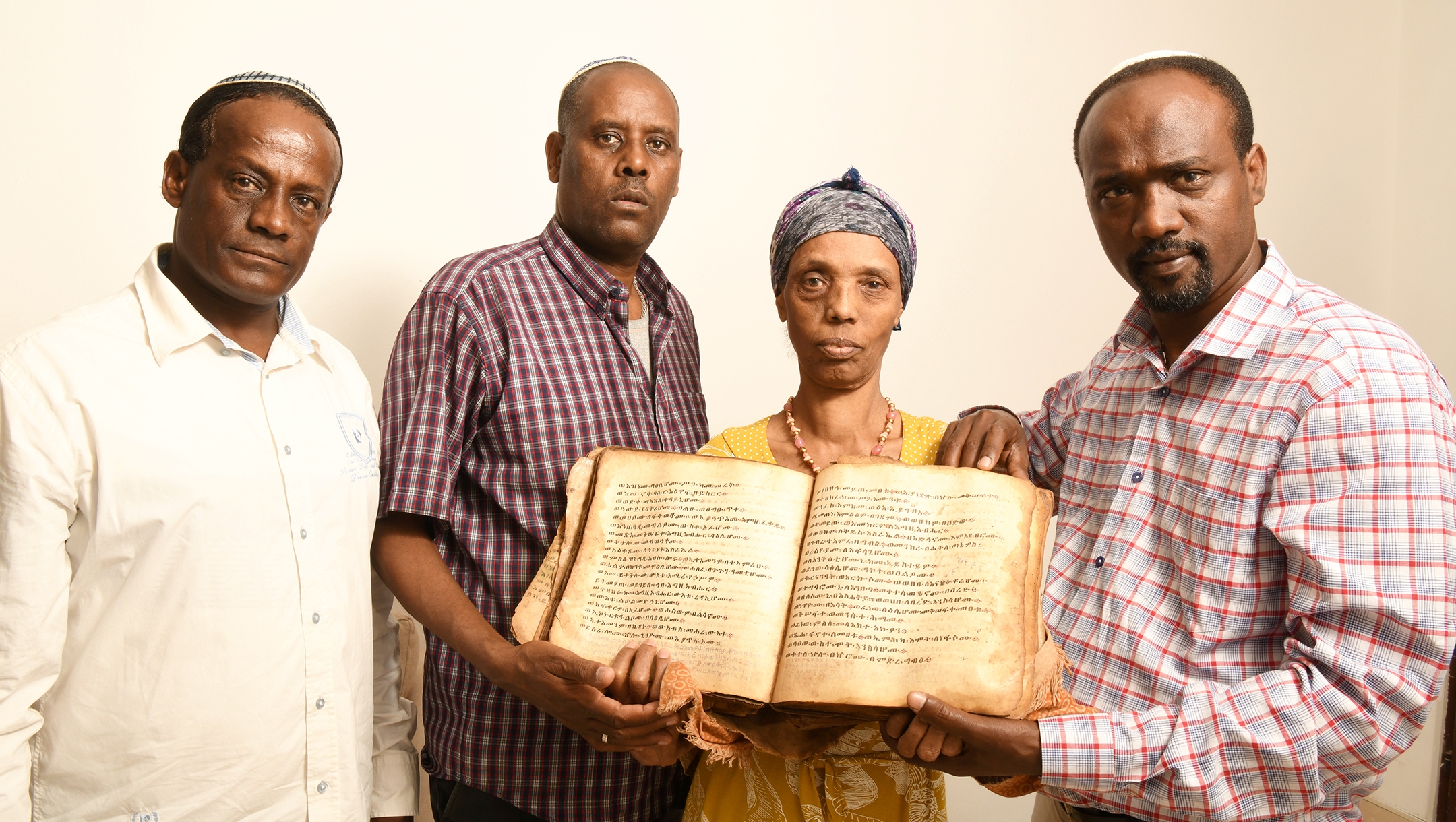 Ayanawo Ferada Senebato, right, and his family shown in Ashkelon, Israel, holding an ancient Orit book that they retrieved near Gondar, Ethiopia, in February 2022. (Yossi Zeliger)