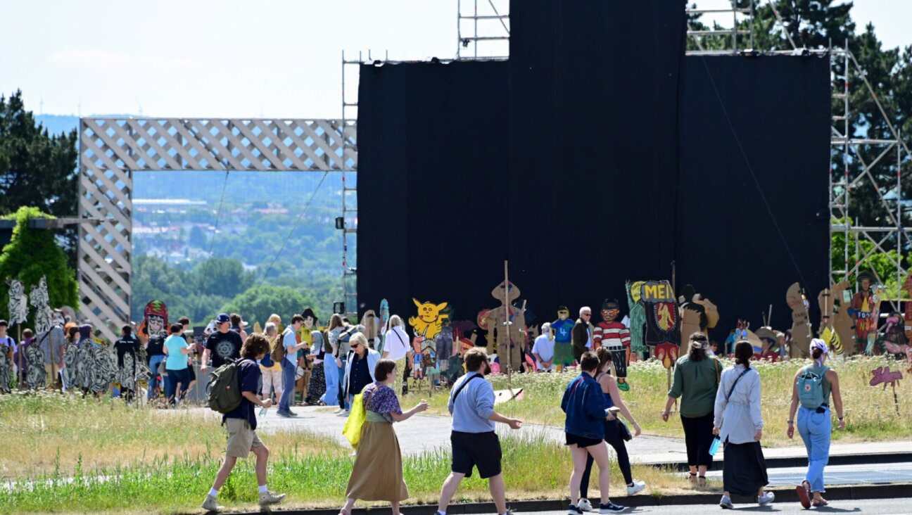 Art lovers look at the large painting “People’s Justice” (2002) by the Indonesian collective Taring Padi, covered with black cloth, on Friedrichsplatz in Kassel, Germany, June 28, 2022. Several antisemitic motifs could be seen on the banner, prompting a debate about the show’s handling of antisemitic content. (Uwe Zucchi/picture alliance via Getty Images)