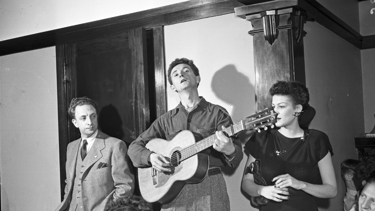 וווּדי גאָטרי באַגלייט זיך מיט דער גיטאַר בעת אַ קאָנצערט אין שיקאַגע, בערך 1940 