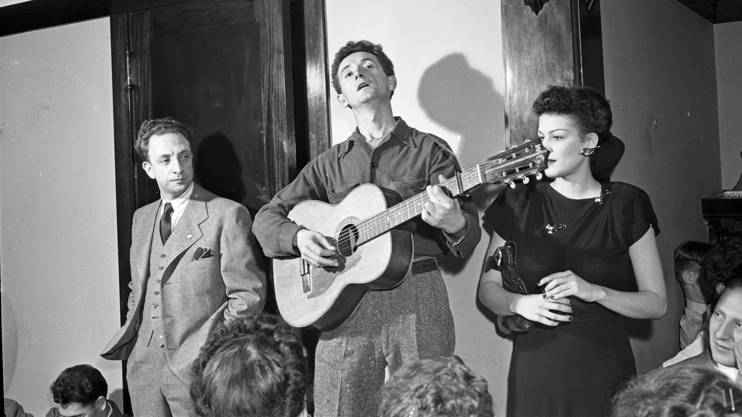 וווּדי גאָטרי באַגלייט זיך מיט דער גיטאַר בעת אַ קאָנצערט אין שיקאַגע, בערך 1940 