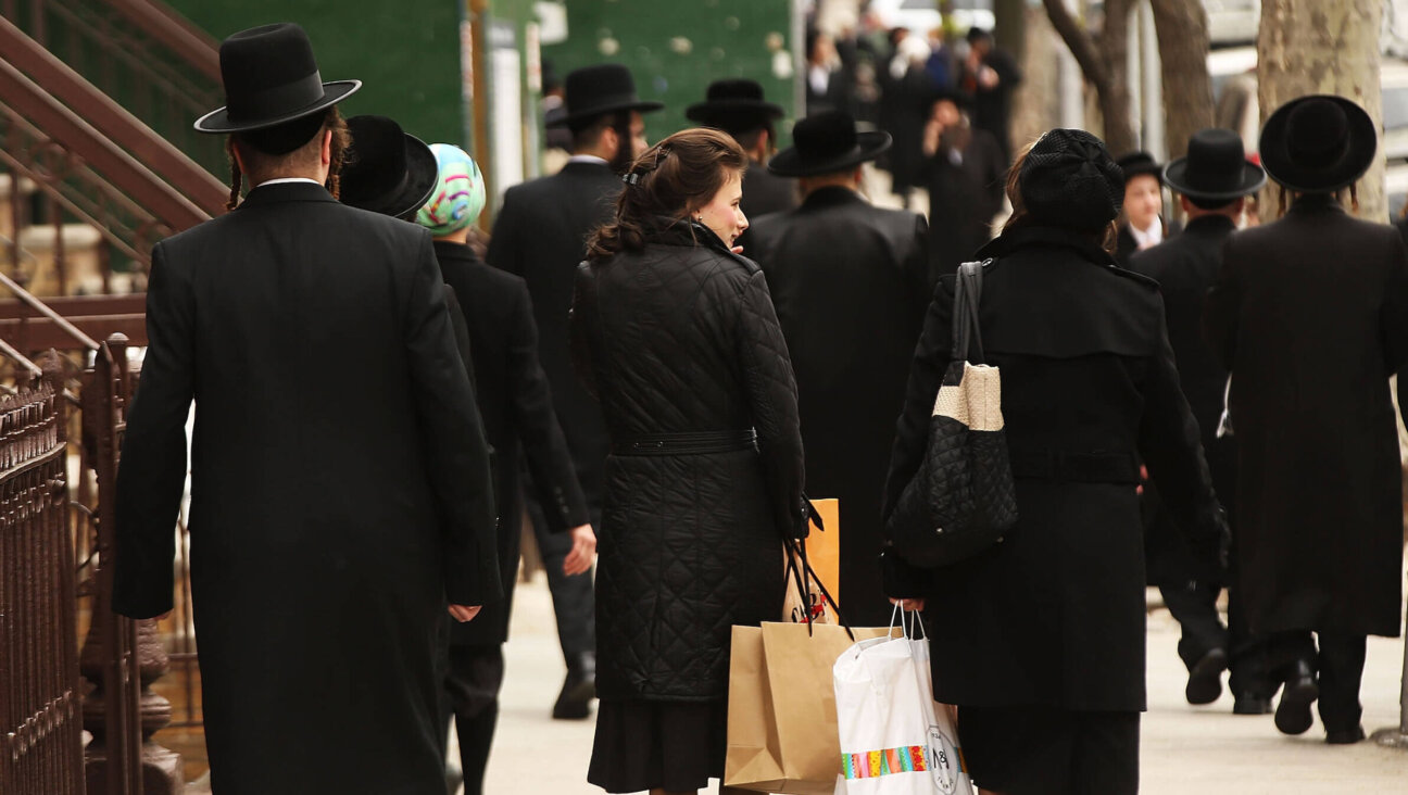 Haredi men and women walk through a Jewish Orthodox neighborhood in Brooklyn.