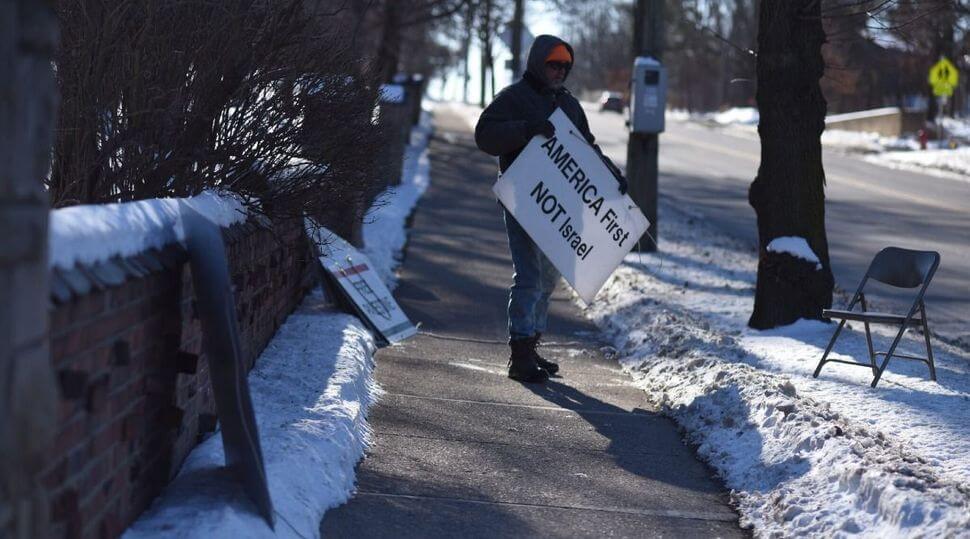 A protester stands outside Beth Israel Congregation in Ann Arbor, Michigan, flanked by anti-Israel and antisemitic signs, in 2020. On Jan. 18, 2022, the Ann Arbor City Council formally condemned the weekly protests, which had been going on for 18 years.