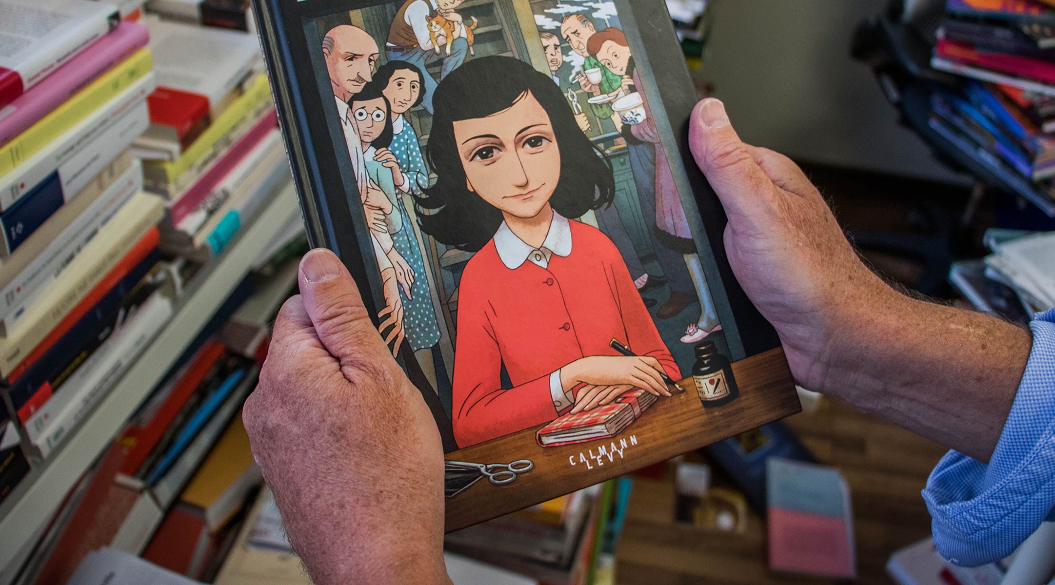 A man holds a copy of the graphic novel version of “The Diary of Anne Frank”, by Israeli writer-director Ari Folman and illustrator David Polonsky, in Paris Sept. 18, 2017. (Stringer/AFP via Getty Images)