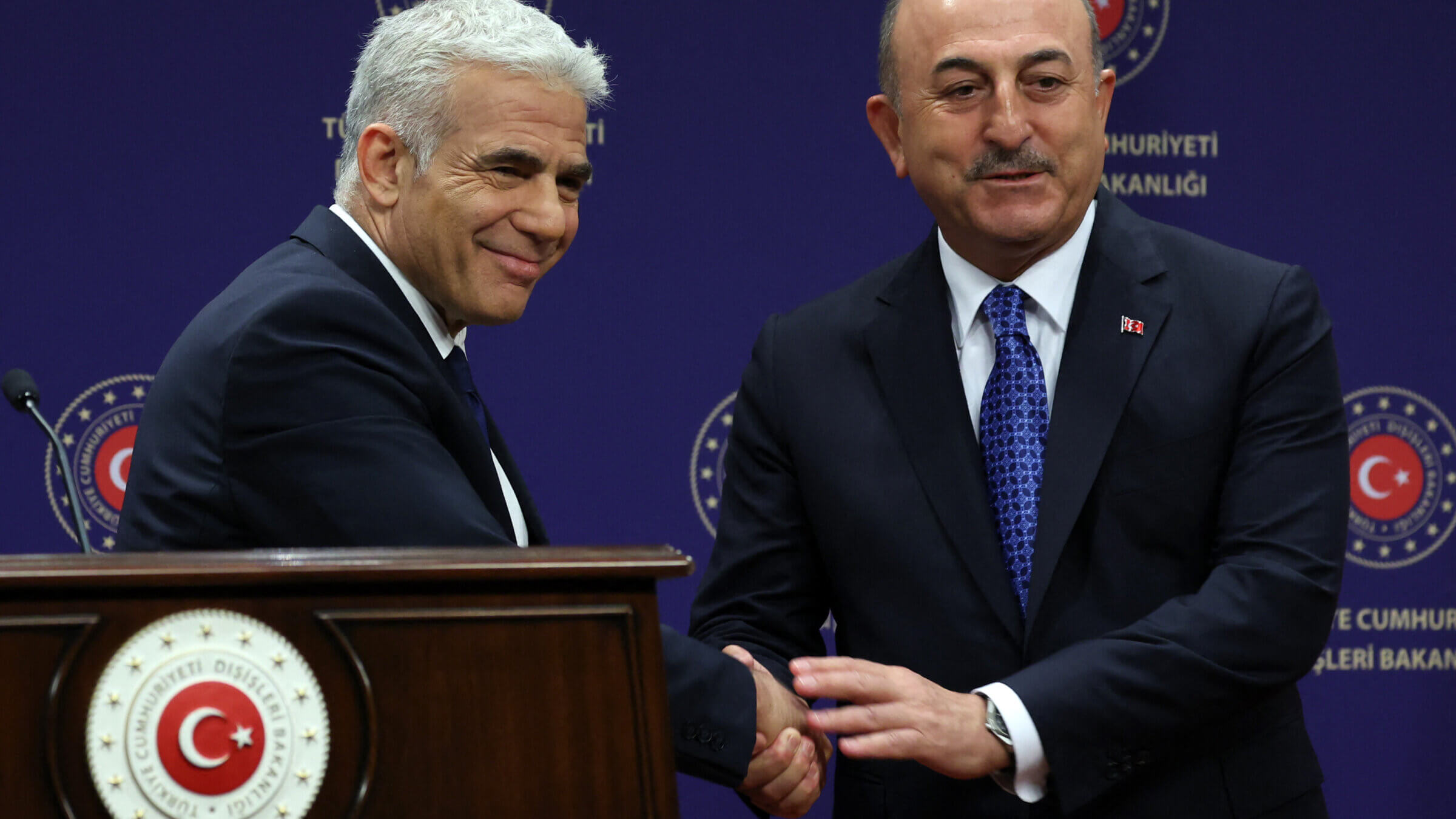 Israel's Foreign Minister Yair Lapid (L) and Turkish Foreign Minister Mevlut Cavusoglu (R) shake hands during a news conference in Ankara, Turkey, on June 23, 2022