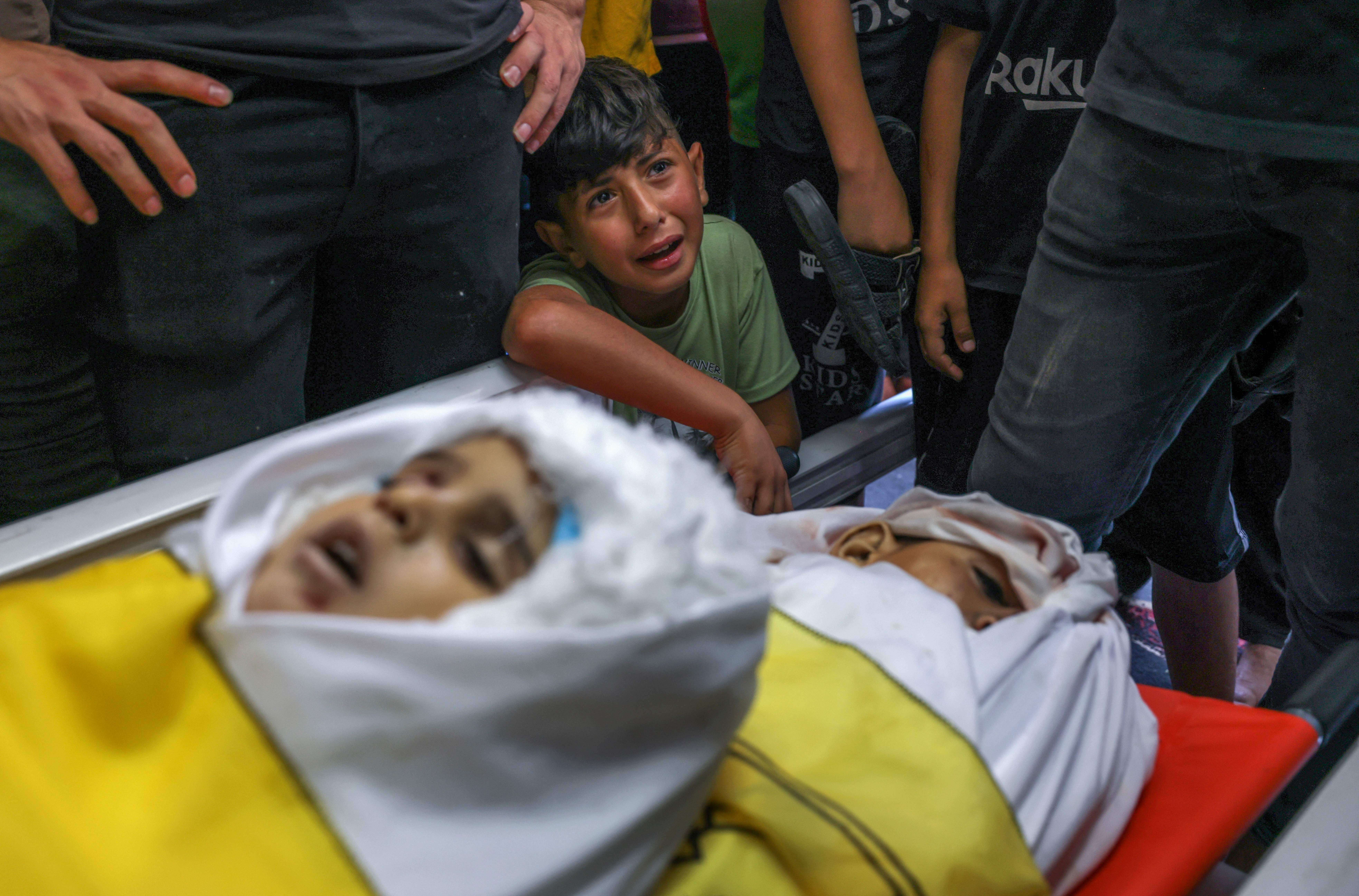 A boy cries by the bodies of four Palestinians from the Najm family during their funeral in Jabalia in the northern Gaza Strip on Aug. 8, 2022, after they were killed during the latest three days of conflict between Israel and Palestinian militants before a ceasefire