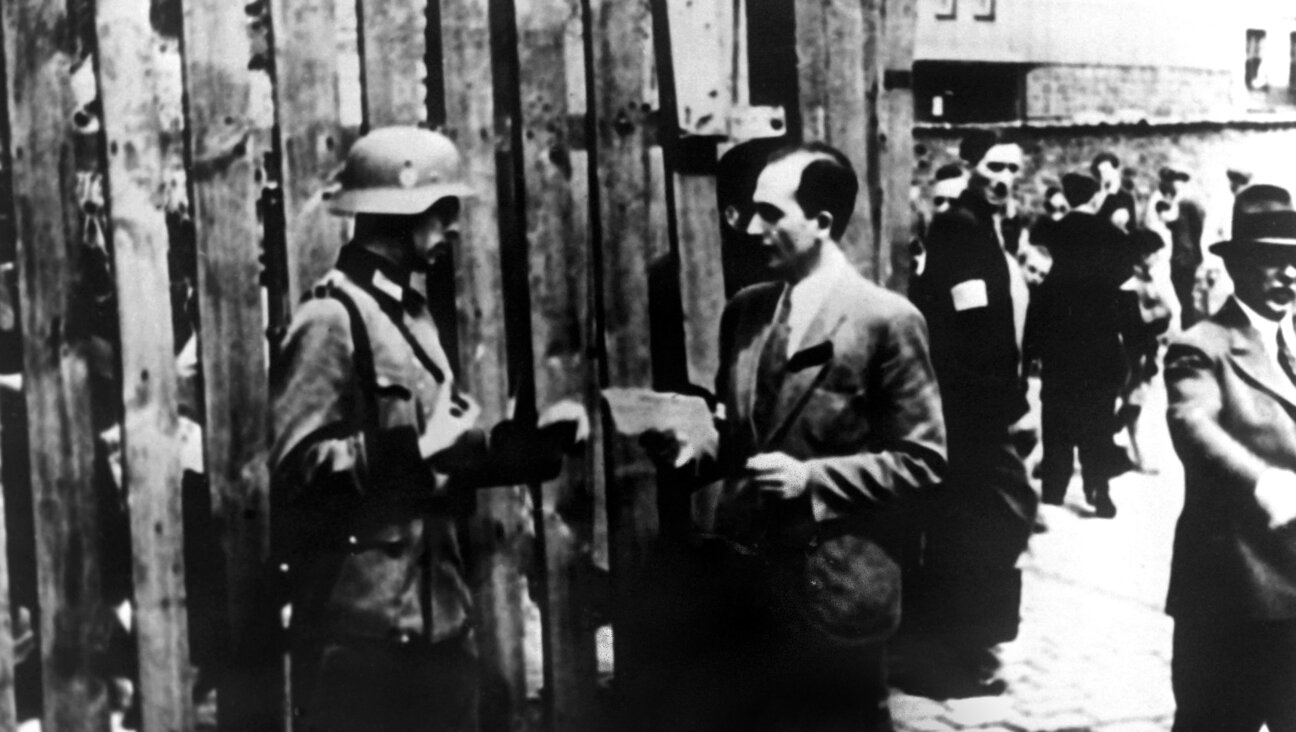 A Nazi soldier checks someone's papers in Warsaw's Jewish ghetto during World War II.