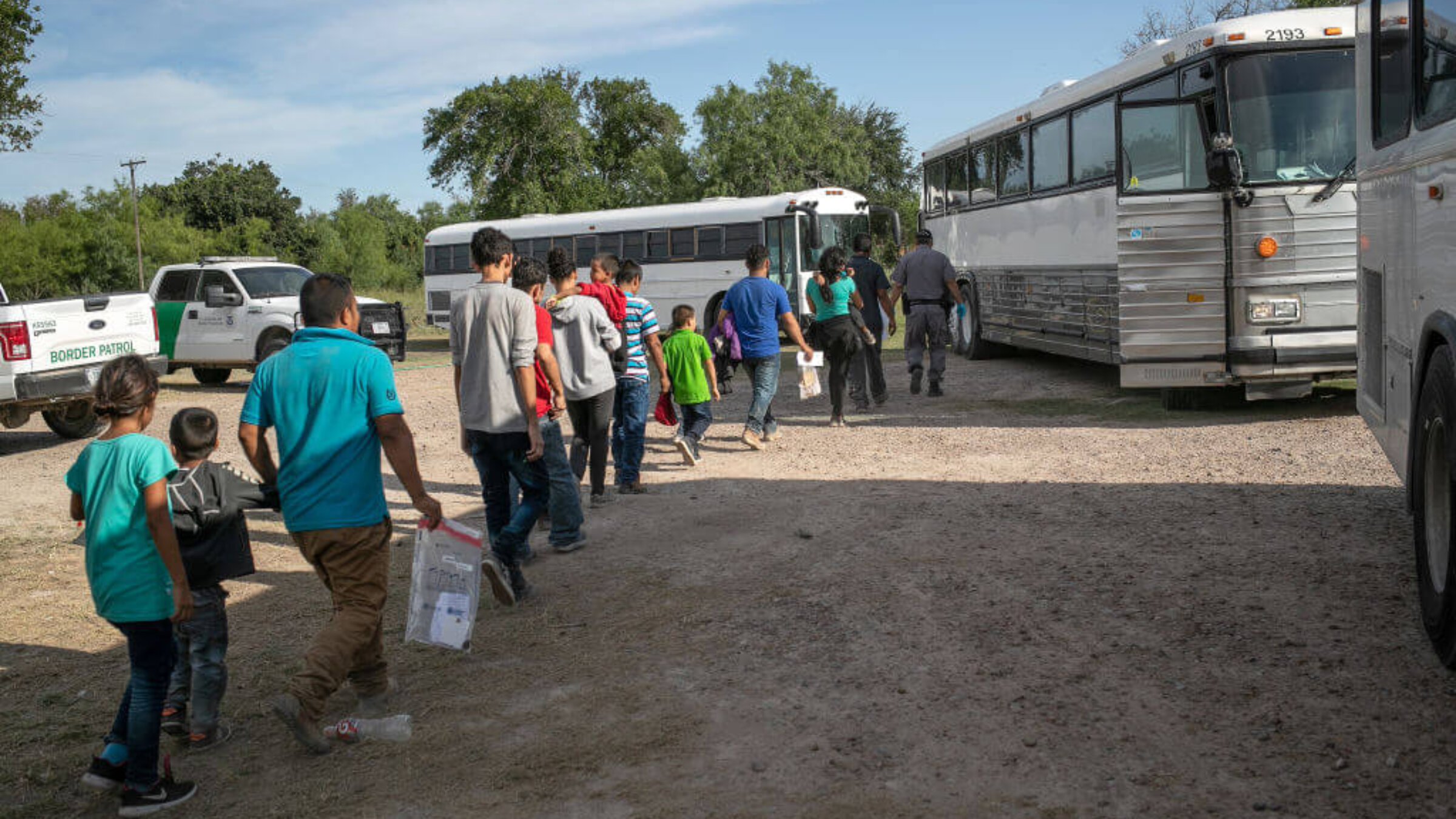 Immigrants walk to U.S. Homeland Security busses to be transferred to a U.S. Border Patrol facility in McAllen after crossing from Mexico on July 02, 2019 in Los Ebanos, Texas. 