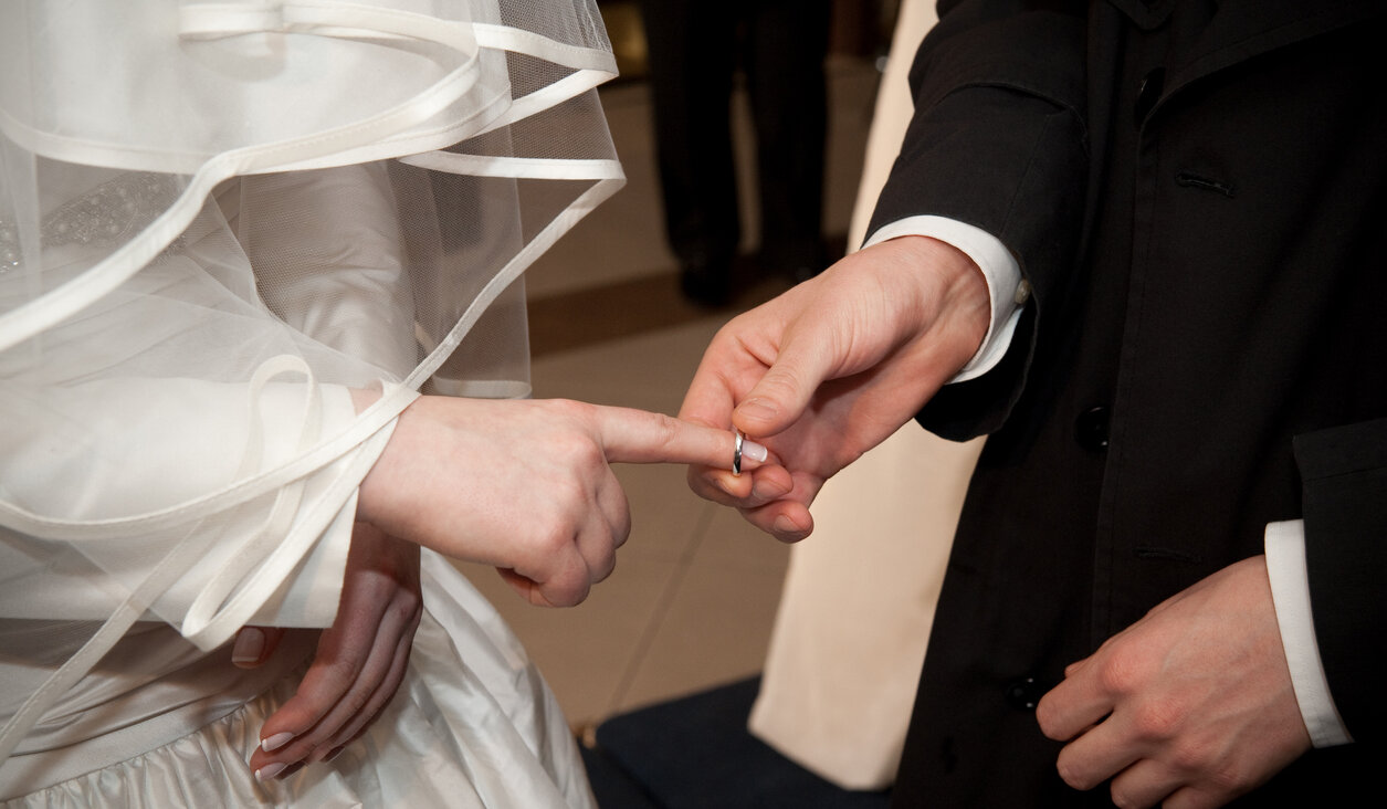 A groom puts a ring on the bride's index finger in an Orthodox Jewish wedding ceremony