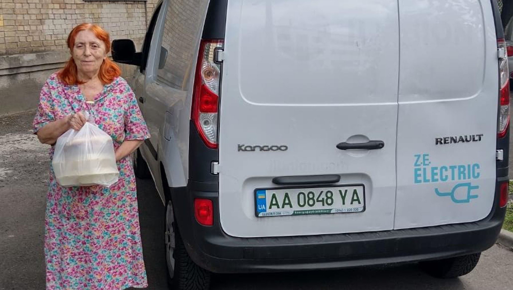 A woman takes out an aid package from an electric car owned by the Jewish Federations of Ukraine in Kyiv, Ukraine, Aug. 1, 2022. (Courtesy of the Jewish Federations of Ukraine.)