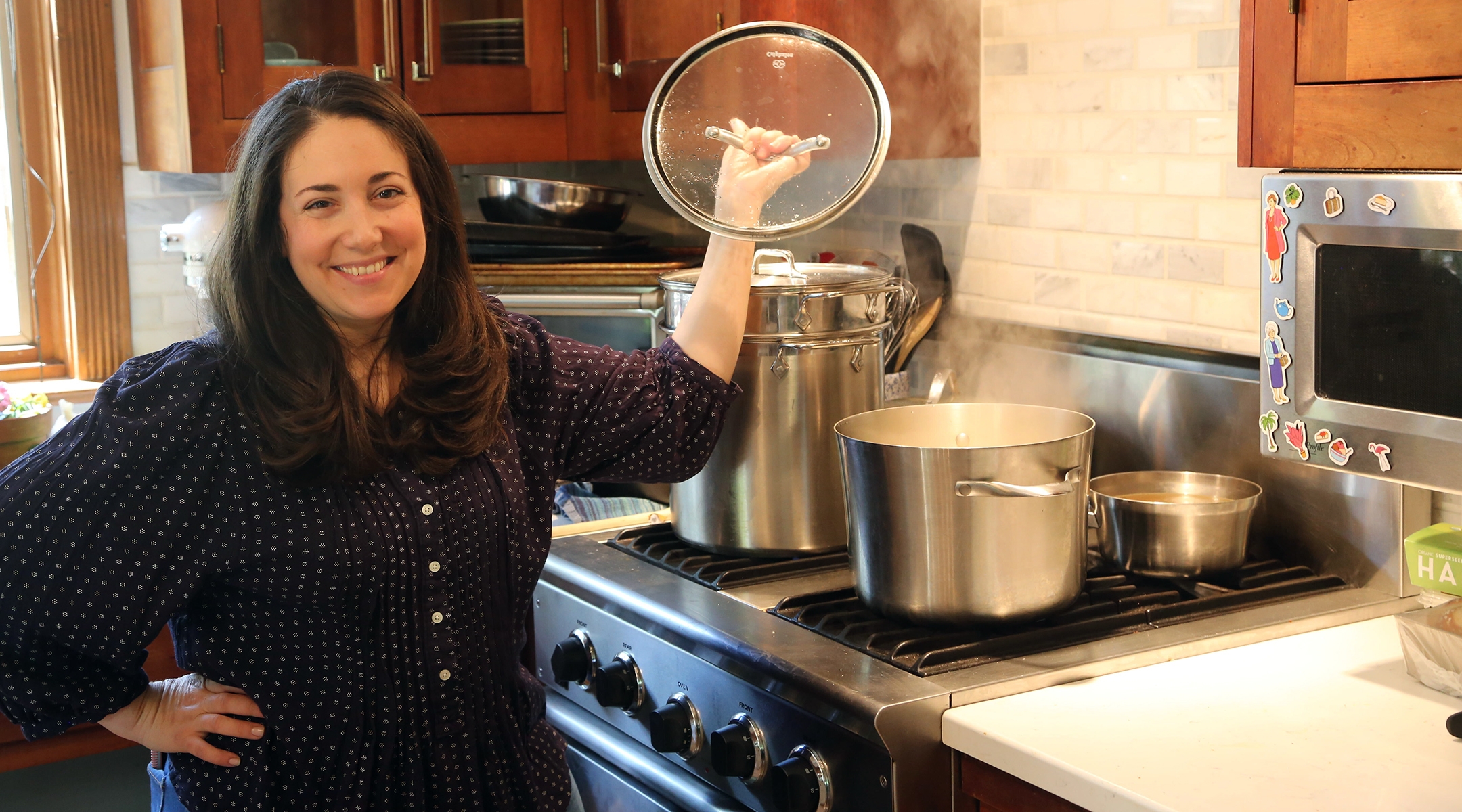 Shannon Sarna, author of “Modern Jewish Comfort Food,” stands over a pot of chicken soup, one of the many comfort food recipes in her new book. (Doug Schneider)