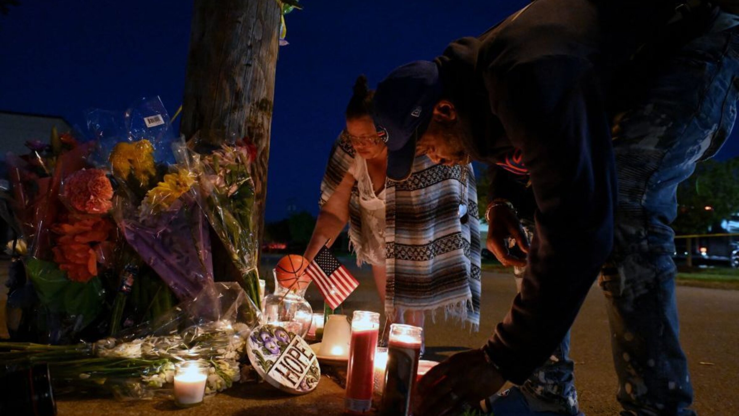 People light candles at a makeshift memorial near a Tops Grocery store in Buffalo, New York, on May 15, 2022, the day after a gunman shot dead 10 people. 