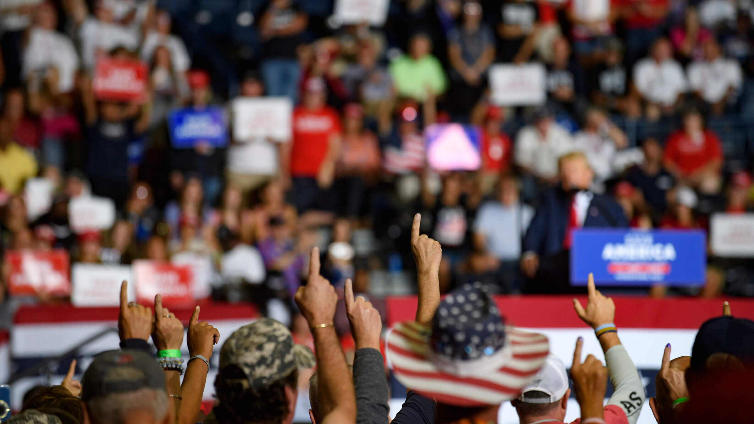 Audience members put their index finger up while President Donald Trump speaks at a Save America Rally.