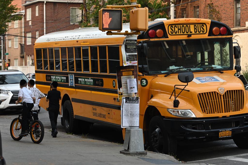People walk past a yeshiva school bus in Borough Park on September 25, 2020.