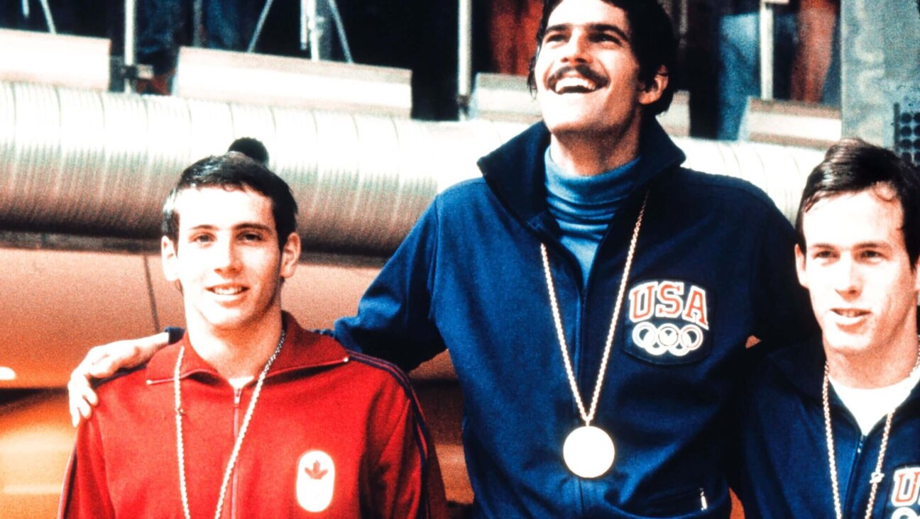 Mark Spitz, center, smiles on the podium after winning the gold medal in the 100-meter butterfly ahead of Bruce Robertson, left, and Jerry Heindenreich, right, Aug. 31, 1972, at the Olympic Games in Munich.