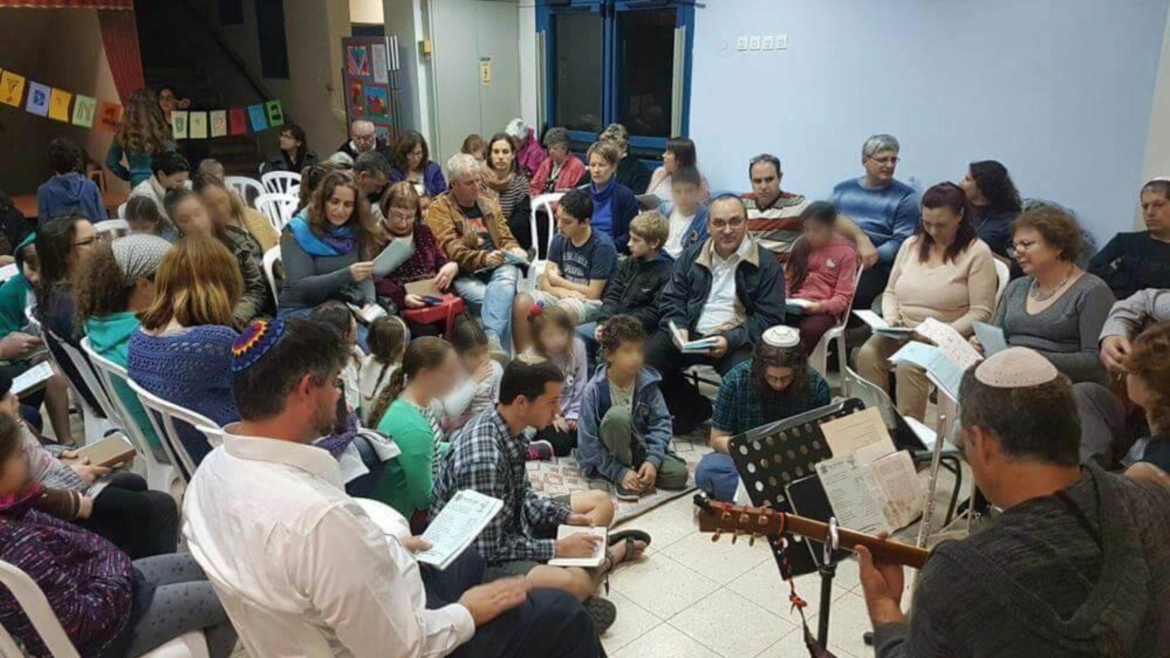 The Yuval congregation prays together inside a cramped school classroom. 