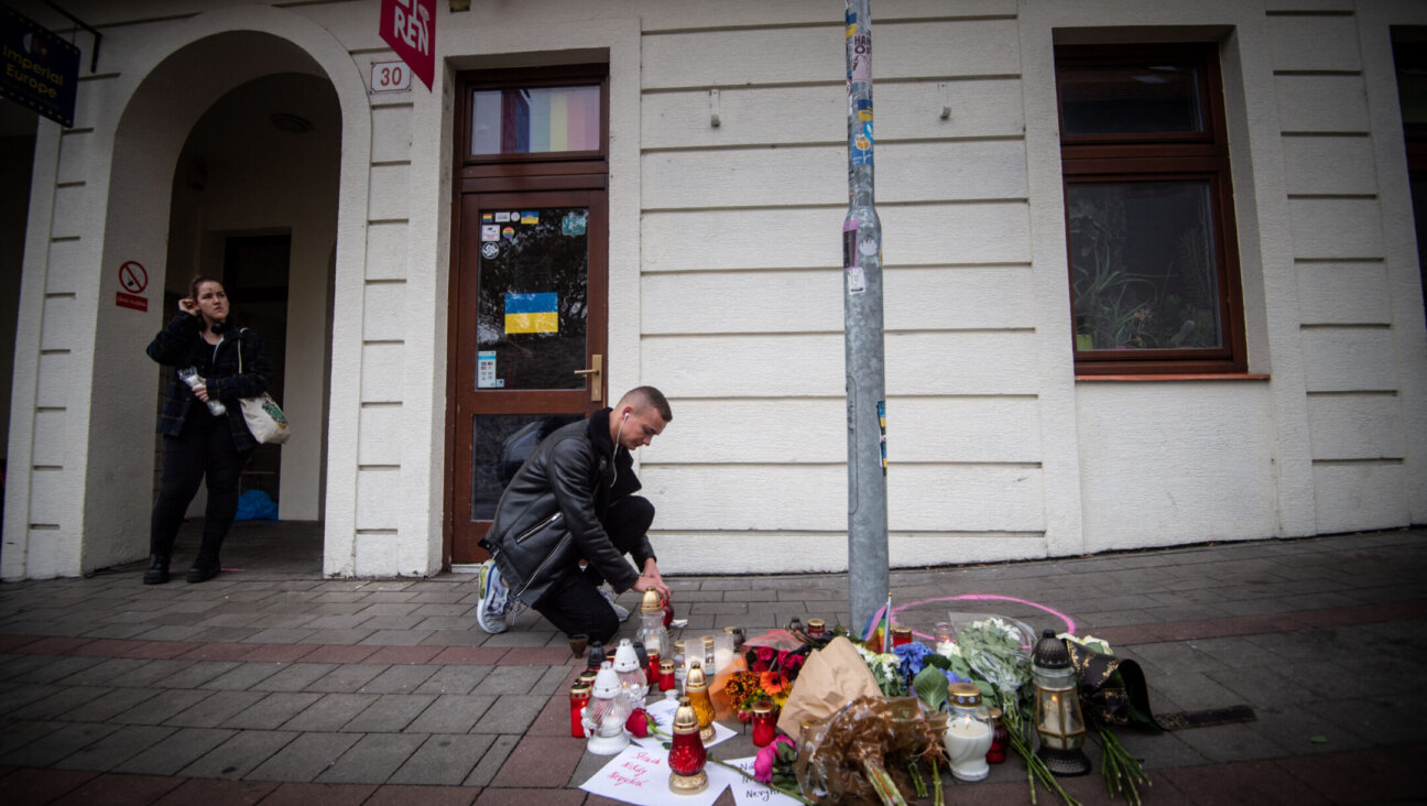 A man places a candle on the pavement at Zamocka Street in Bratislava after a “radicalized teenager” murdered two men there, Oct. 13. 2022 (Photo by Vladimir Simicek/AFP via Getty Images)