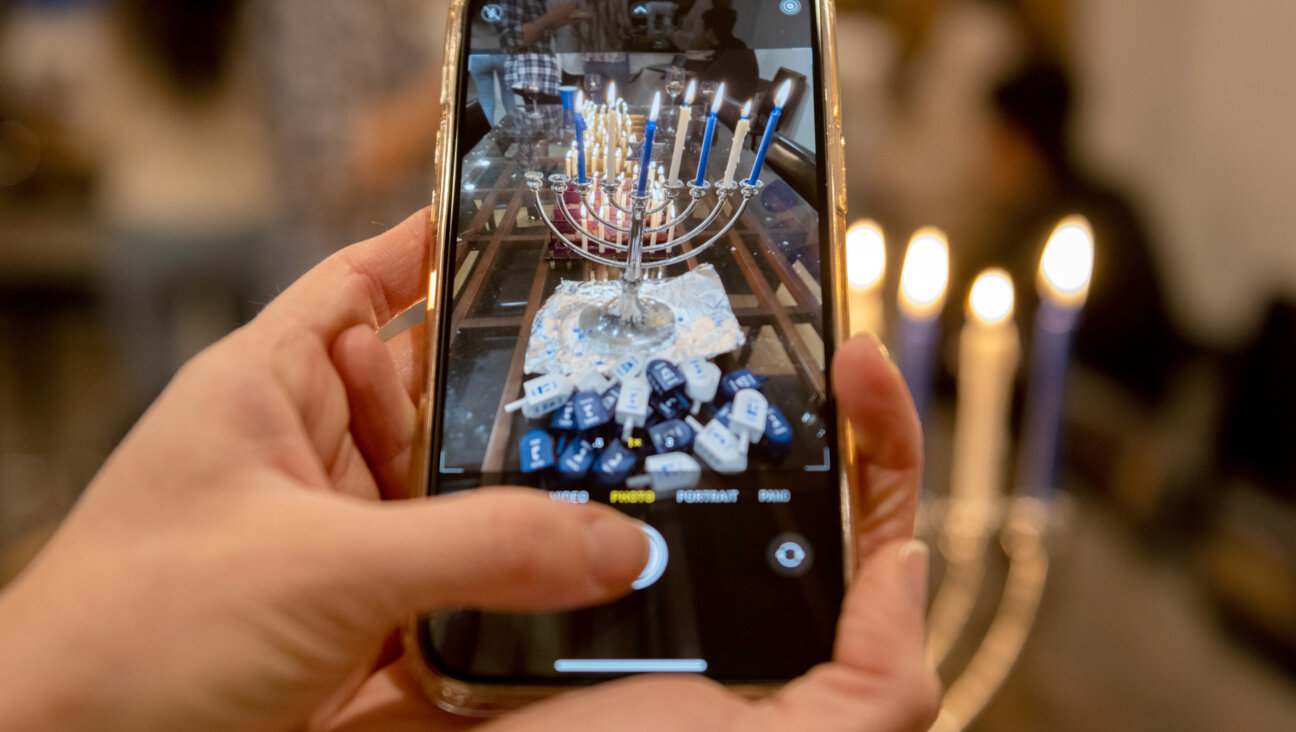 A woman takes a cellphone photo of menorahs lit for Hanukkah