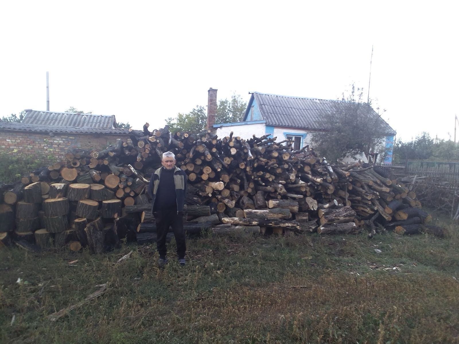 An elderly Jewish man in the Dnipro region of Ukraine stands before a delivery of firewood made by JDC as part of an effort to support Ukrainian Jews in advance of a punishing winter. (Courtesy of the JDC)