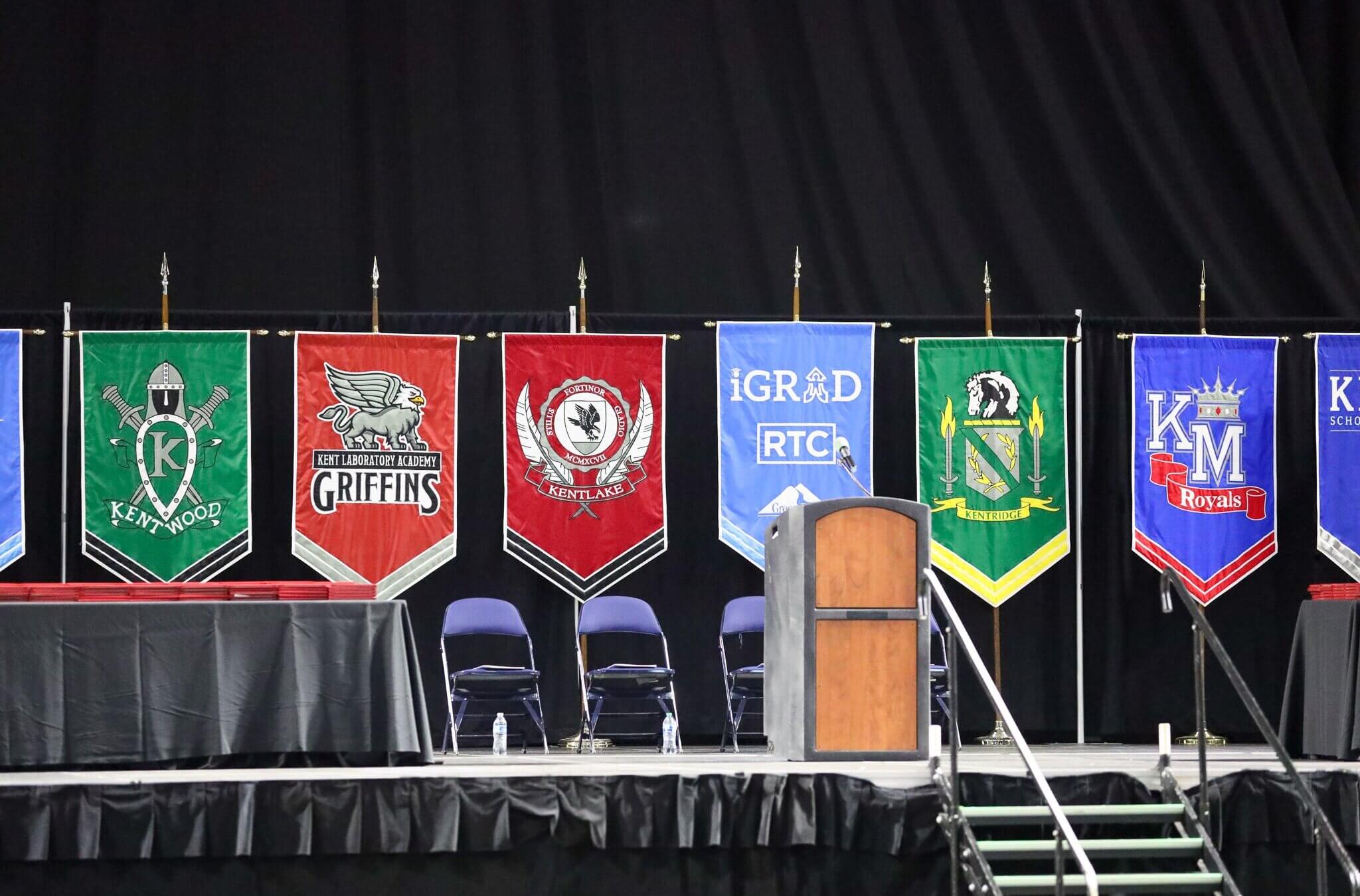 Banners featuring schools from the Kent School District are displayed on stage during a graduation ceremony last spring. An official with the district said this week that school libraries might be required to offer books disputing the Holocaust.