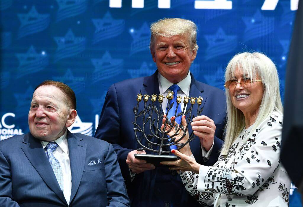 President Donald Trump poses with Sheldon and Miriam Adelson at en event in December 2019.