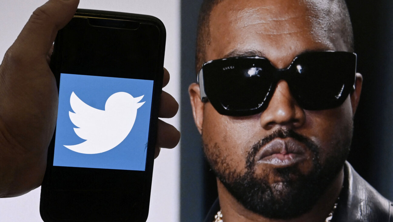 The Twitter logo is displayed on a mobile phone with a photo of Kanye West in the background.