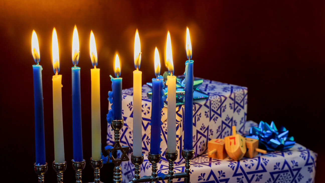 Lit Hanukkah menorah with wrapped gifts