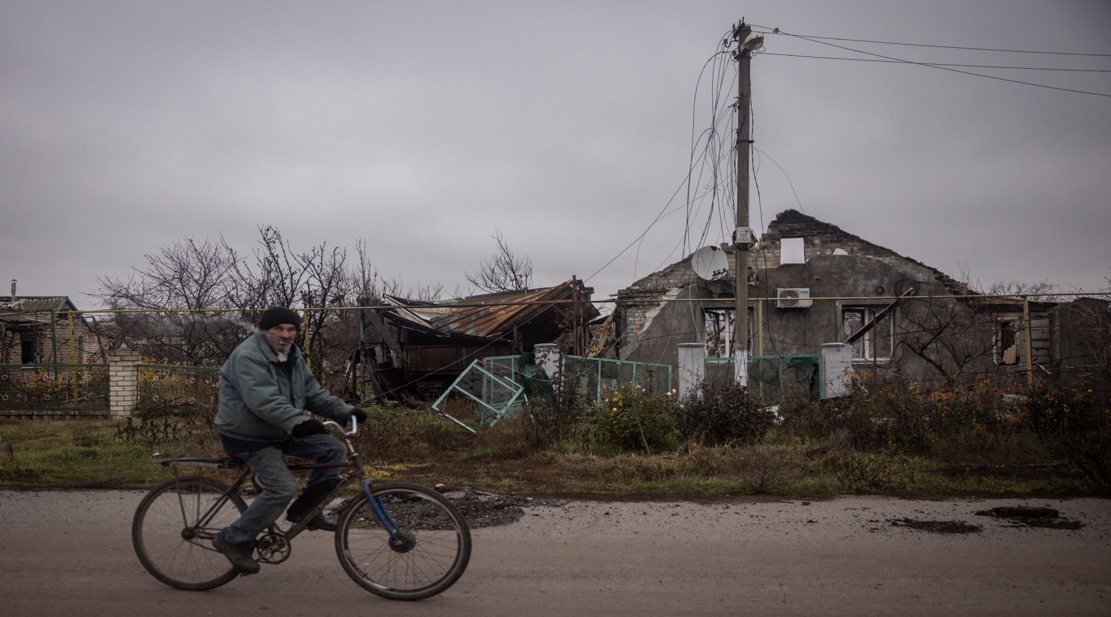 A man rides a bike past a destroyed house in the village of Posad Pokrovske on the outskirts of Kherson on November 30, 2022 in Kherson, Ukraine. Recently Ukrainian forces took back control of Kherson, as well as swaths of its surrounding region, after Russia pulled its forces back to the other side of the Dnipro river. Kherson was the only regional capital to be captured by Russia following its invasion on February 24. (Photo by Chris McGrath/Getty Images)