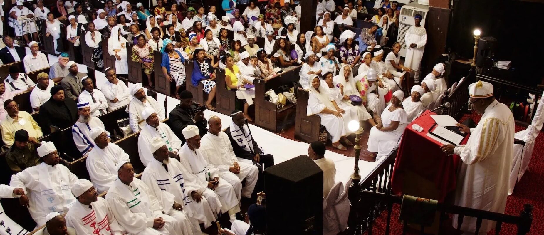 Congregants and clergy crowd the sanctuary of B'nai Adath Kol Beth Yisrael, an Israelite synagogue in Brooklyn, New York.