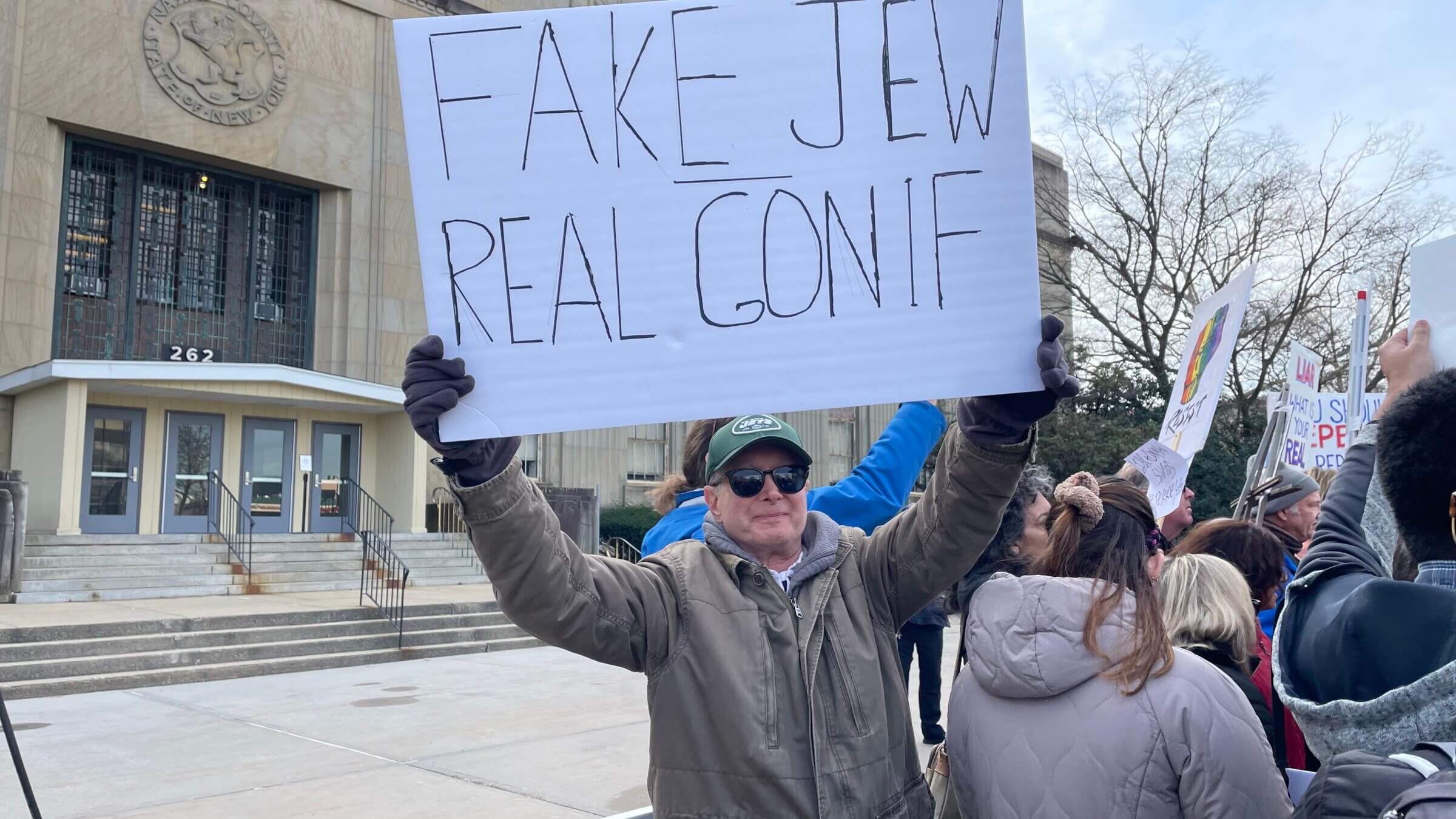 A protester holds up a sign against Rep.-elect George Santos on Dec. 29, 2022.